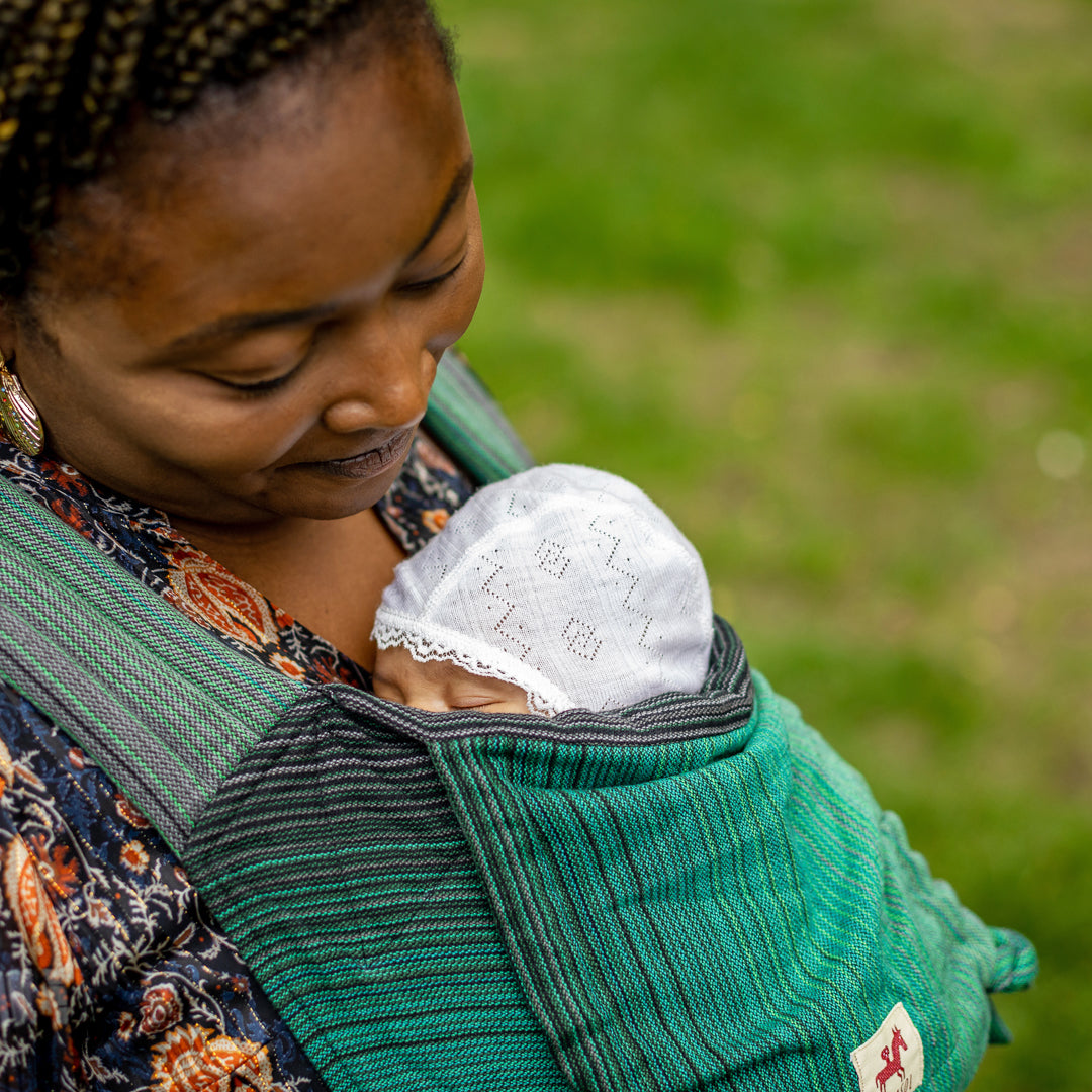 Mutter blickt liebevoll auf kleines Baby in Mysol Tragegurt Cunning