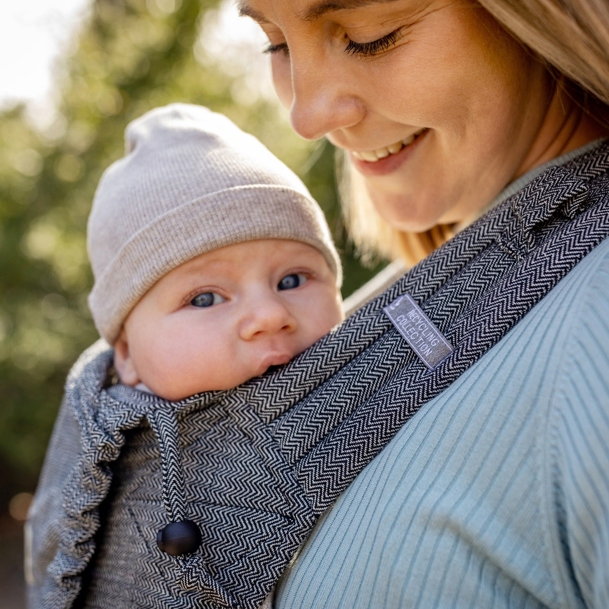 Mutter lächelt Baby an in Mysol Tweed